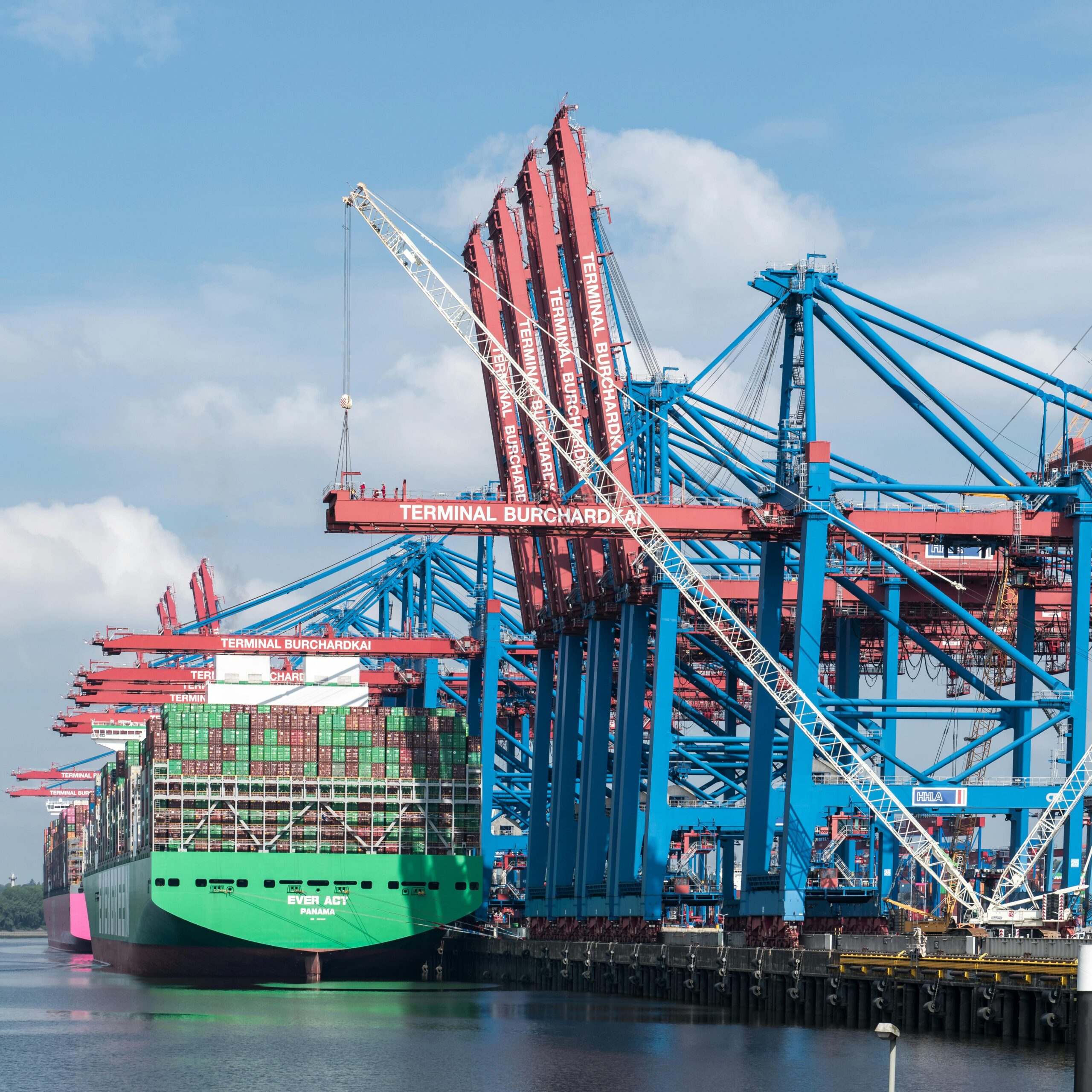 Cranes and container ships at Terminal Burchardkai in Hamburg port on a clear day.